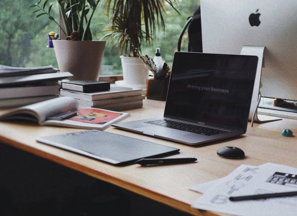 A modern home workspace with a laptop, plants, and stationery